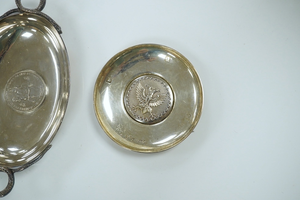 A 1970's Brittania standard silver commemorative small dish, C. Hoare & Co, London, 1972, 92mm, together with a German 925 oval dish with serpent handles and inset with coin, gross 8.9oz. Condition - fair